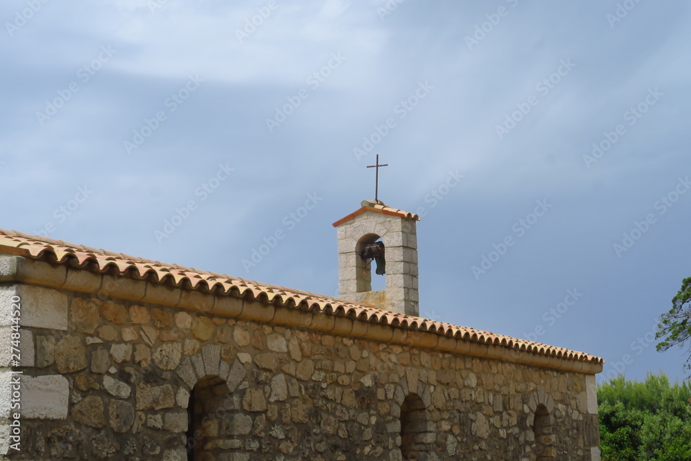 Petite chapelle avec toit de tuiles et petit clocher.