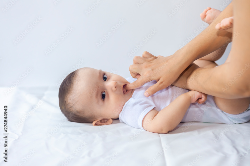 Baby boy teething pain. Little 6-month baby having teeth pains. Mother rubbing gel to her little baby boy's teeth Baby boy teething pain. Little 6-month baby having teeth pains. Mother rubbing gel to her little baby boy's teeth