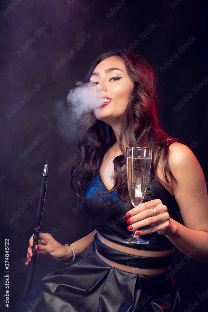 Nice woman smoking shisha and drinking cocktail in a bar