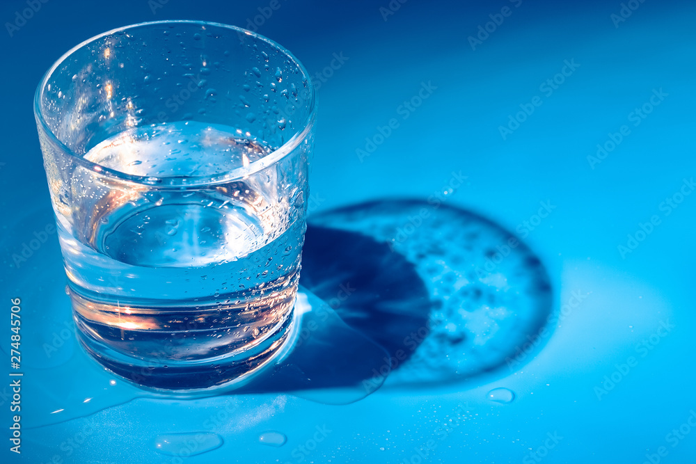A glass with water drops on a dark blue background close up A glass with water drops on a dark blue background close up