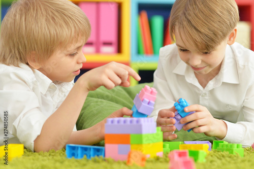 Two boys playing with colorful plastic blocks on floor