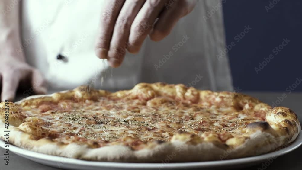 Professional cook finishing pizza with oregano Professional cook finishing pizza with oregano