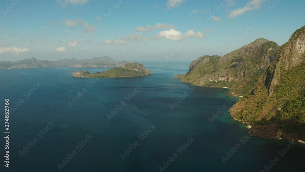 Fototapeta premium Seascape with tropical bay, rocky islands, ocean blue water, aerial view. islands and mountains covered with tropical forest. El nido, Philippines, Palawan. Tropical Mountain Range