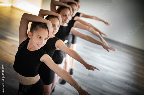 Group of fit happy children exercising dancing and ballet in studio together