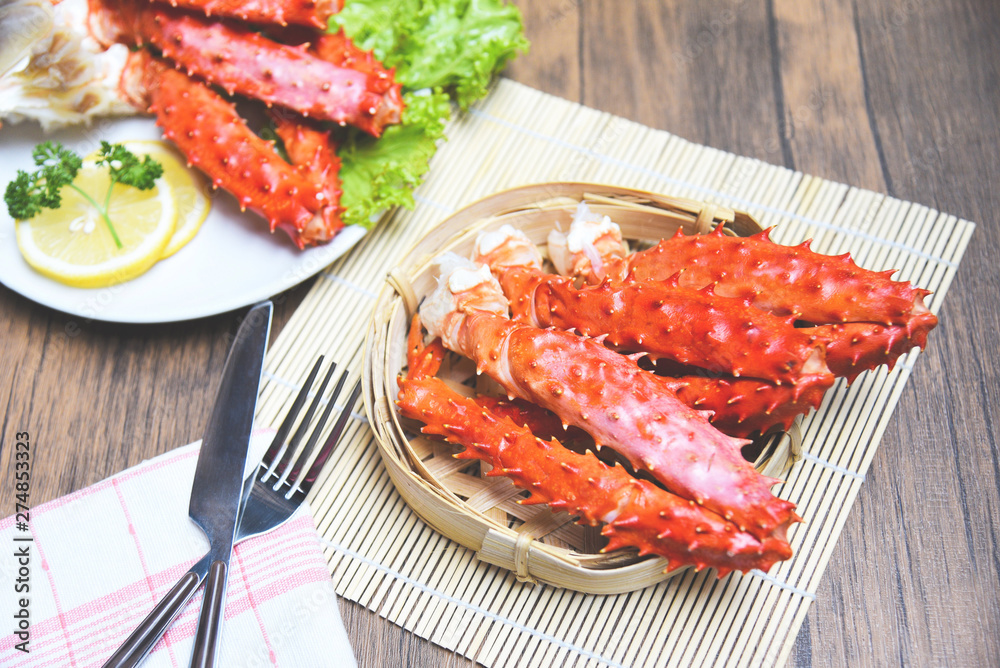 Alaskan King Crab Legs cooked seafood with lemon spices on white plate in the wooden table - red crab hokkaido Alaskan King Crab Legs cooked seafood with lemon spices on white plate in the wooden table - red crab hokkaido