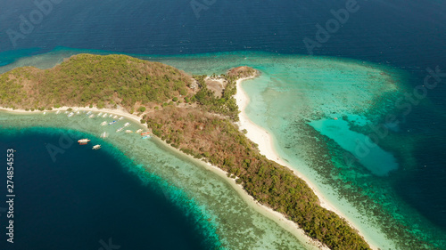 Aerial drone Island in blue lagoon with sandy beach and coral reef. Malcapuya, Philippines, Palawan. Tropical landscape with blue lagoon, coral reef