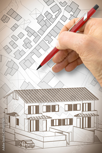 Architect drawing a duplex residential building over an imaginary cadastral map of territory with buildings, fields and roads