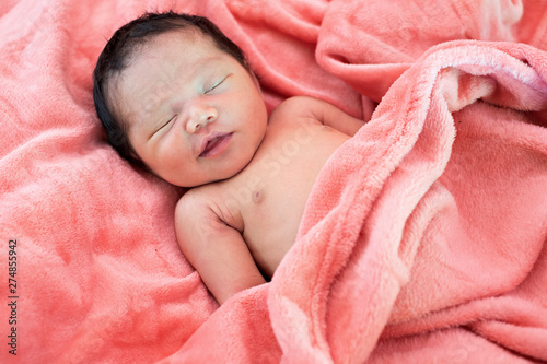 Newborn baby girl sleeping in pink cloth.
