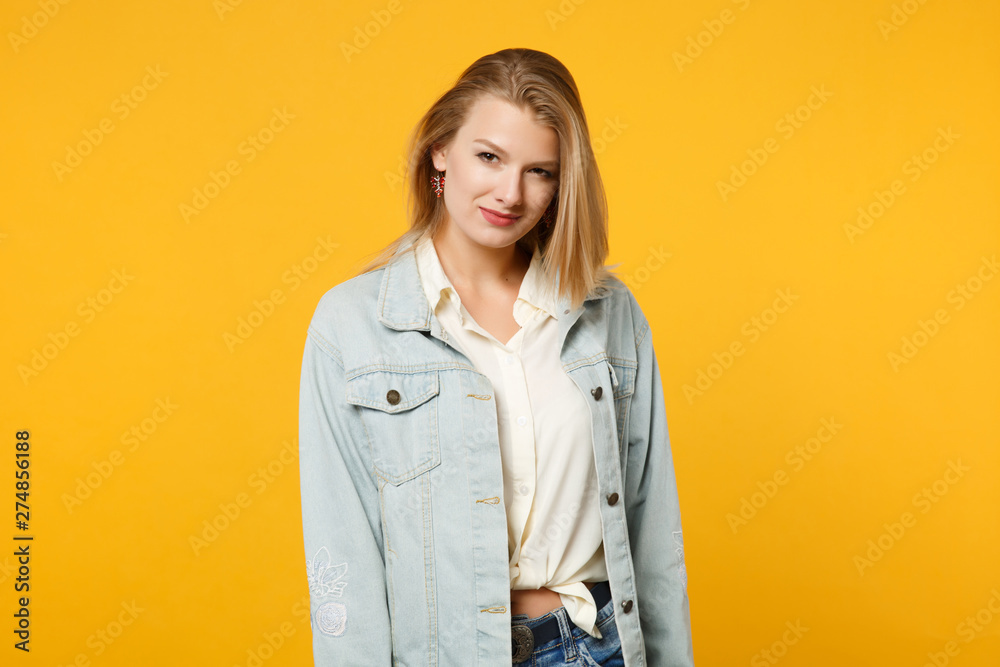 Portrait of attractive beautiful young woman in denim casual clothes standing, looking camera isolated on bright yellow orange wall background in studio. People lifestyle concept. Mock up copy space. Portrait of attractive beautiful young woman in denim casual clothes standing, looking camera isolated on bright yellow orange wall background in studio. People lifestyle concept. Mock up copy space.