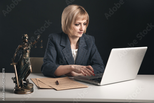 Woman attorney sitting at a workplace and working laptop. Female lawyer concept