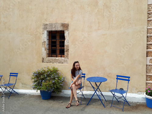 Beautiful woman sitting in cute vintage street. Crete, Greece