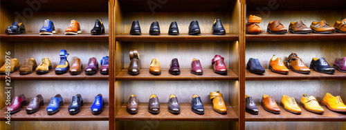 Full grain leather shoes on wooden display in men shoes boutique store. Black, brown and other colors.