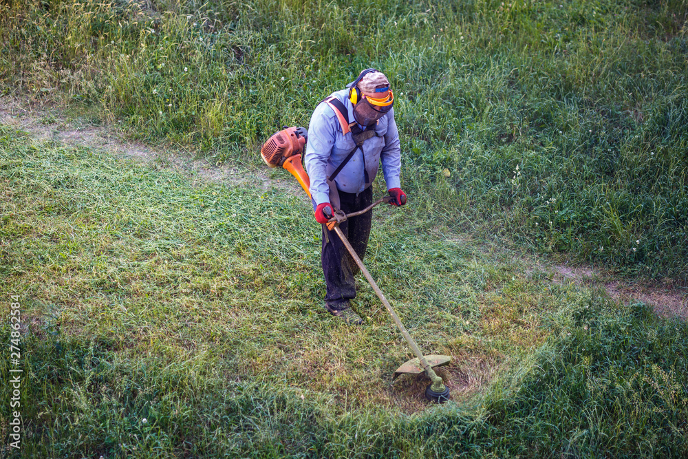 Top view fat dirty lawnmover man worker cutting dry grass with lawn mower. Top view fat dirty lawnmover man worker cutting dry grass with lawn mower.