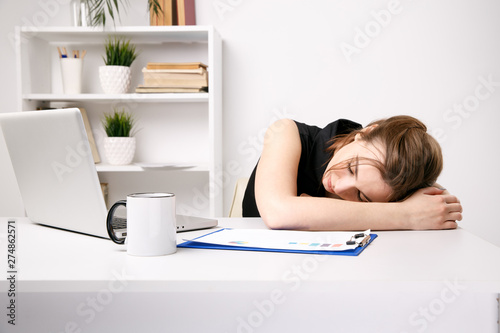 Young businesswoman feeling sleepy at her work place in office