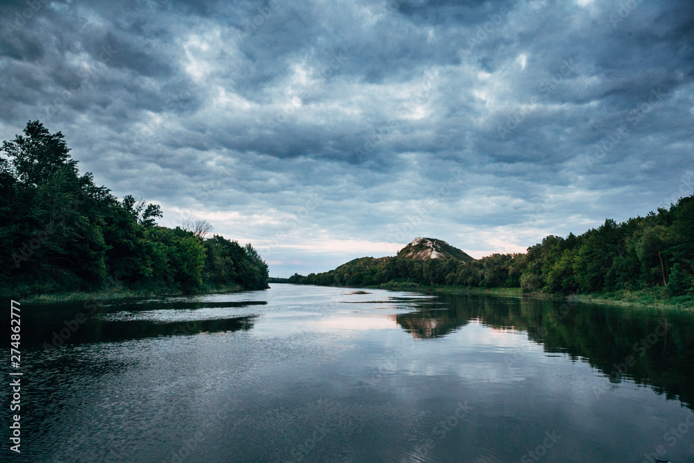 Fototapeta premium cloudy sky on the river in the summer evening