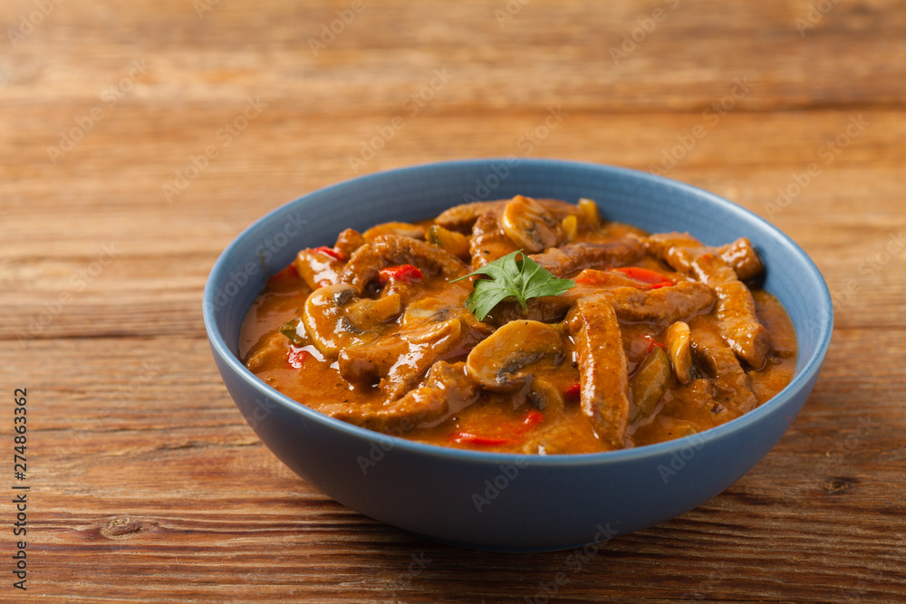 Boeuf, Stroganow, Strogonow. Classic, Russian beef stew. Served in a blue bowl. Front view. Natural background. Boeuf, Stroganow, Strogonow. Classic, Russian beef stew. Served in a blue bowl. Front view. Natural background.