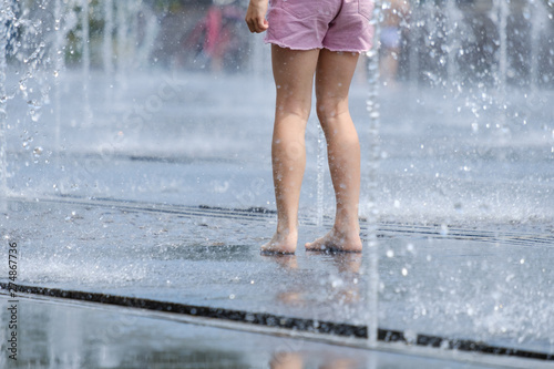 Fototapeta Naklejka Na Ścianę i Meble -  Bare feet for children in a refreshing spray of the city fountain on a hot summer day