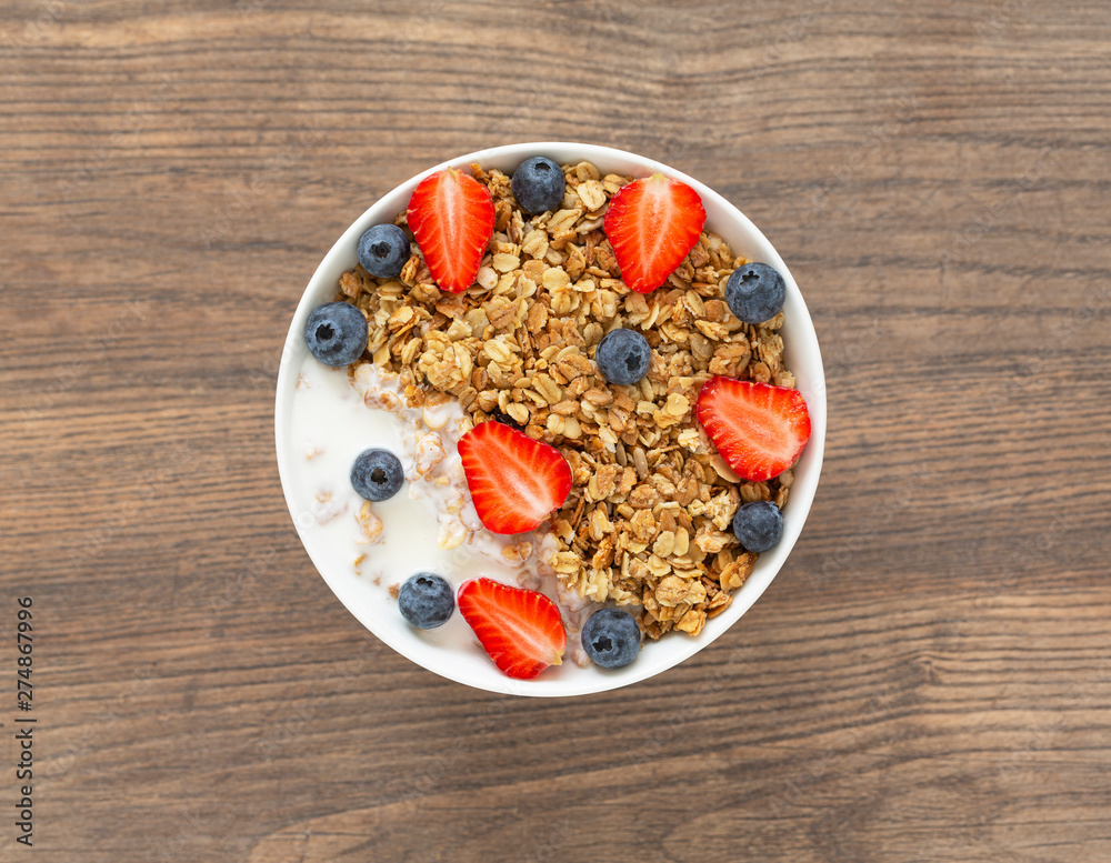 Healthy smoothie bowl with granola, yogurt, strawberry and fresh blueberries on wooden background. Breakfast smoothie bowl, top view. Healthy smoothie bowl with granola, yogurt, strawberry and fresh blueberries on wooden background. Breakfast smoothie bowl, top view.