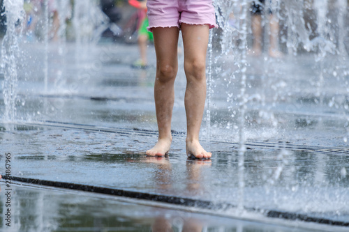 Bare feet for children in a refreshing spray of the city fountain on a hot summer day