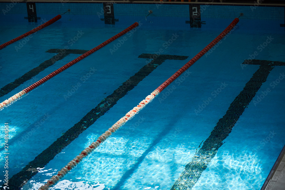 Water surface in the sports swimming pool. Blue water and swim lane dividers. Sports and health concept.