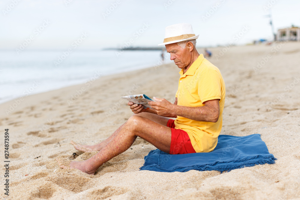Happy mature man  sitting and looking at booklet
