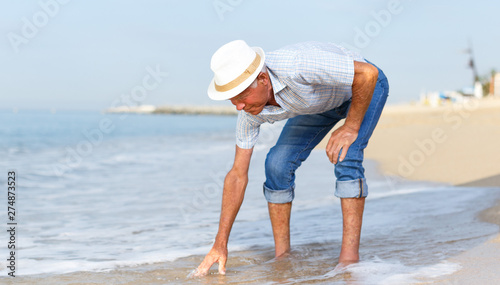 Elderly nice man checks the water temperature