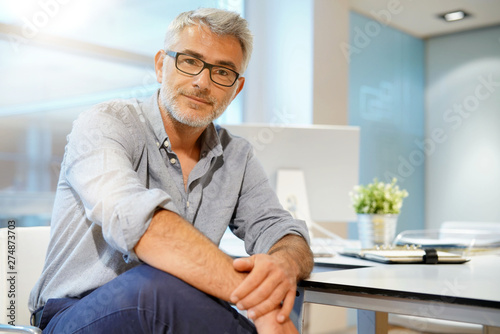 Portrait of smart casual businessman looking at camera in contemporary office photo
