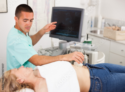 Man examination woman at abdomen with ultrasonography device