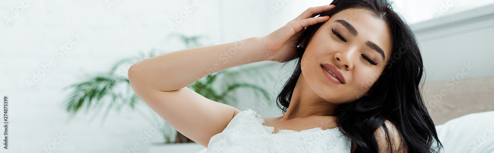 panoramic shot of happy asian girl with closed eyes touching hair panoramic shot of happy asian girl with closed eyes touching hair