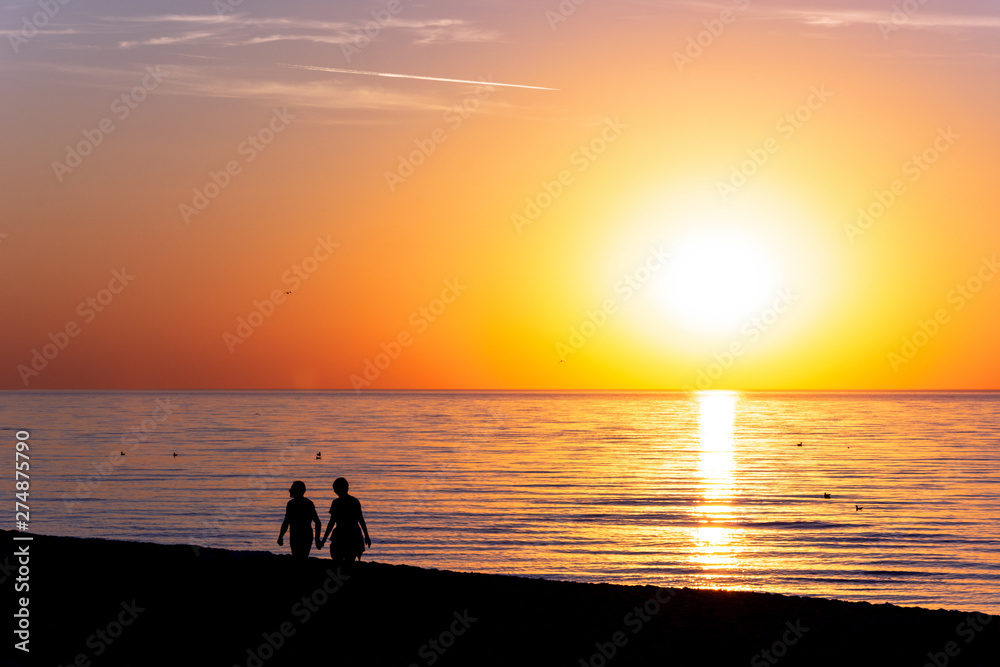 couple silhouette walking beach on sunset