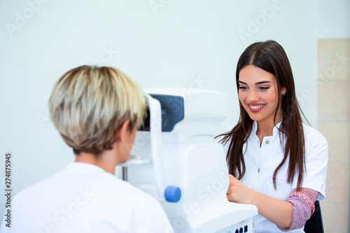 Female doctor ophthalmologist is checking the eye vision of attractive young woman in modern clinic. Doctor and patient in ophthalmology clinic.