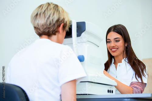 Female doctor ophthalmologist is checking the eye vision of attractive young woman in modern clinic. Doctor and patient in ophthalmology clinic.