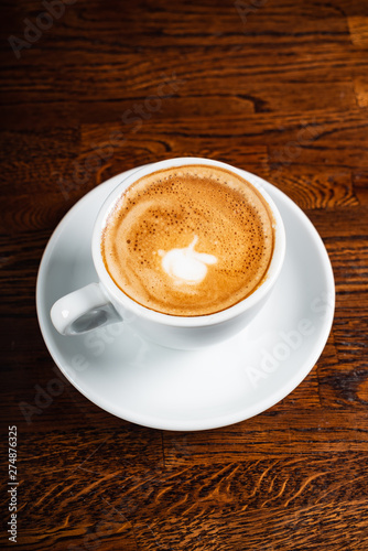 cup of cappuccino on the wooden background