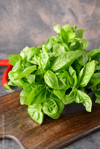Board with fresh green basil on grunge background