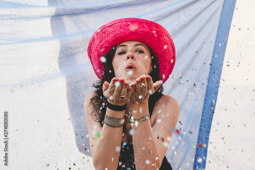pretty woman with colorful straw hat blowing confetti © Marino Bocelli