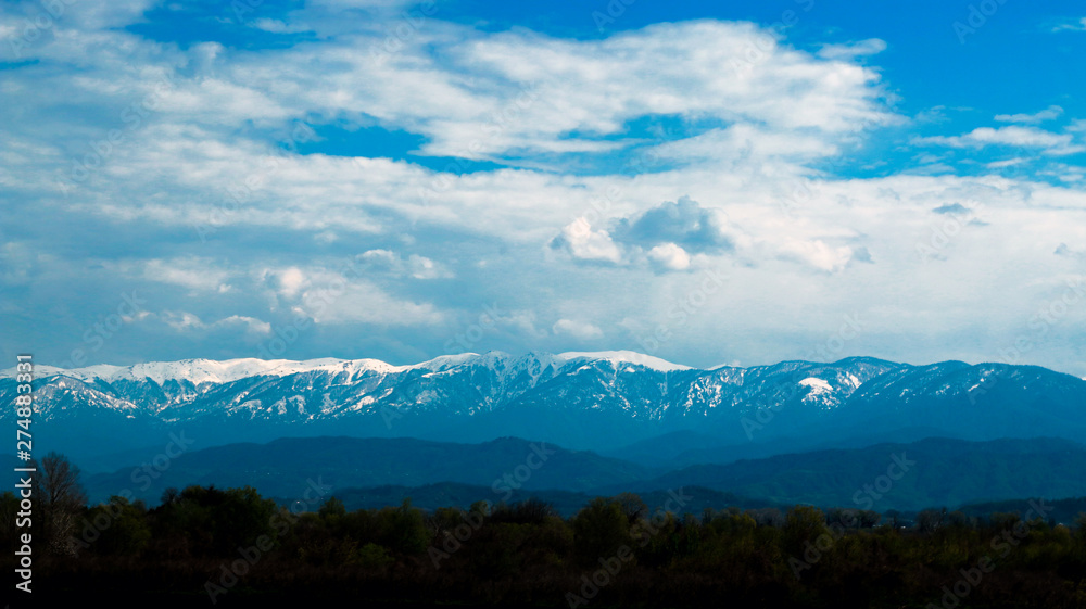 Caucasus. View on Caucasus snow covered mountains and blue sky with clouds on background.