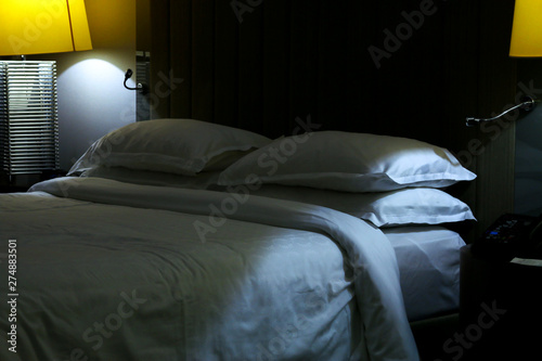 Hotel room with double bed and yellow lamps. 