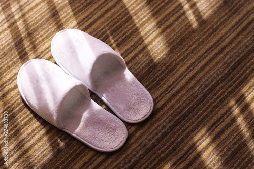 Slippers. White slippers on hotel carpet and sun glares. 