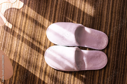 Slippers. White slippers on hotel carpet and sun glares. 