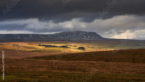 Storm clouds and sunshine over the Three Peaks Summit of Pen-y-ghent near Horton in Ribblesdale in the Yorkshire Dales, England.