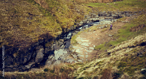 Fotografia A distant hiker at the entrance to Gaping Gill Cave in the limestone rock of the Yorkshire Dales, England