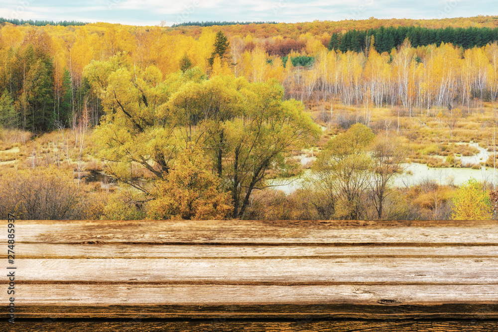 Empty wooden table with picturesque autumn landscape of view from the hill to the lowland with forest and swamps. Mock up for display or montage products Empty wooden table with picturesque autumn landscape of view from the hill to the lowland with forest and swamps. Mock up for display or montage products