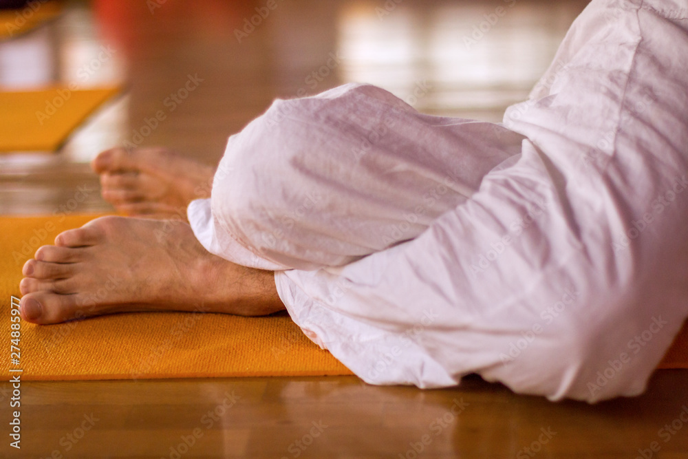 Close up legs in a twisted position called Garuda asana done liying on the mattress.
