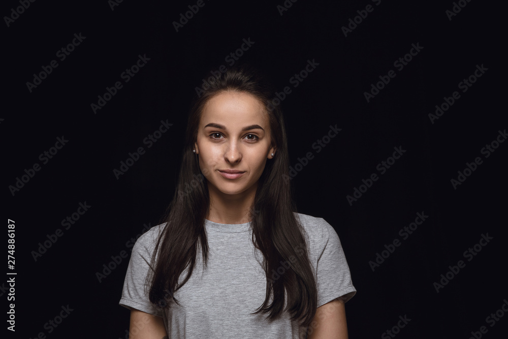 Close up portrait of young caucasian woman isolated on black studio background. Photoshot of real emotions of female model. Standing and looks serious. Facial expression, human nature and emotions Close up portrait of young caucasian woman isolated on black studio background. Photoshot of real emotions of female model. Standing and looks serious. Facial expression, human nature and emotions