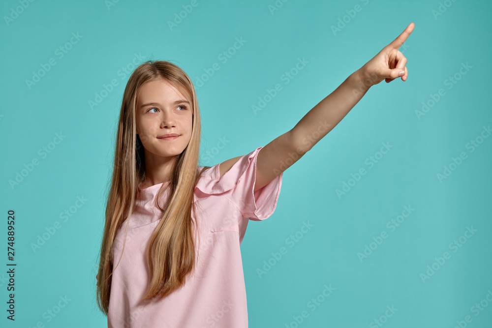 Studio portrait of a beautiful girl blonde teenager in a pink t-shirt posing over a blue background. Studio portrait of a beautiful girl blonde teenager in a pink t-shirt posing over a blue background.