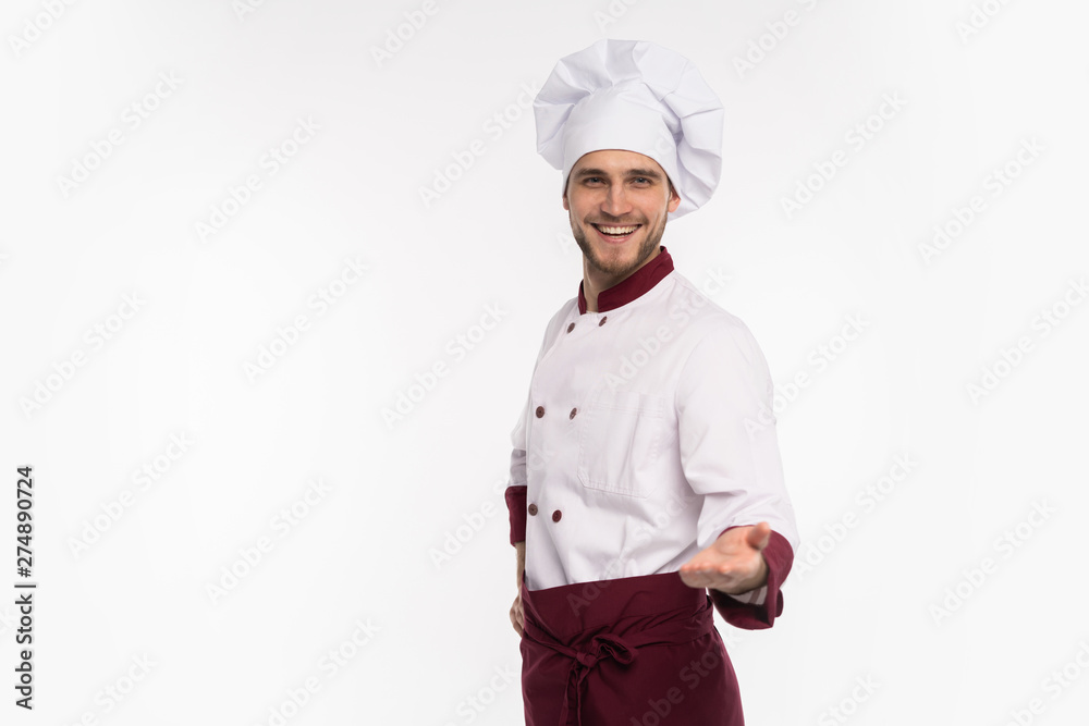 Image of smiling young cook in uniform standing isolated over white background. Looking camera pointing. Image of smiling young cook in uniform standing isolated over white background. Looking camera pointing.