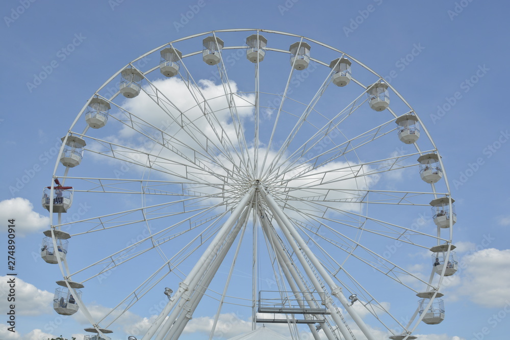 White ferris wheel of the amusement park in the blue sky background.