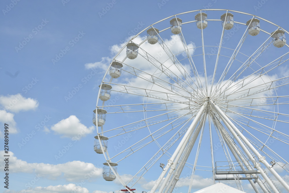 White ferris wheel of the amusement park in the blue sky background. White ferris wheel of the amusement park in the blue sky background.