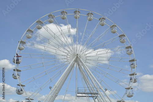 White ferris wheel of the amusement park in the blue sky background.