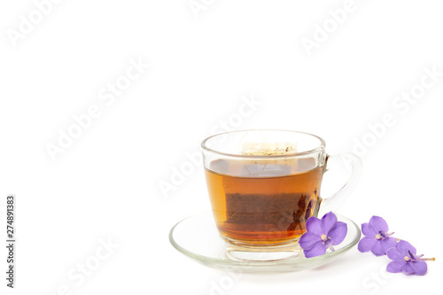 Tea bag in a glass cup with purple flower isolated in white background.